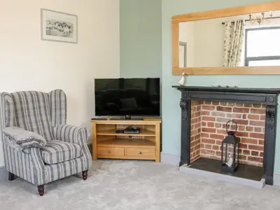 a living room with a fireplace and a chair and a television at The Farm in Presteigne