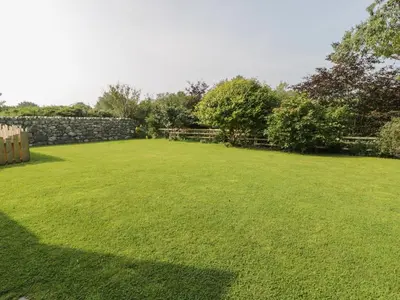 a large yard with a stone wall and green grass at Tyn Ffynnon in Dyffryn