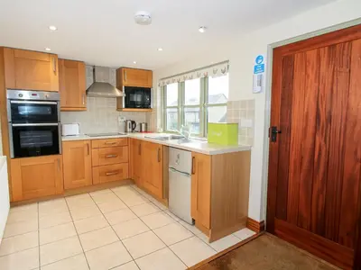 a large kitchen with wooden cabinets and a sink at Norton Cottage in Craven Arms