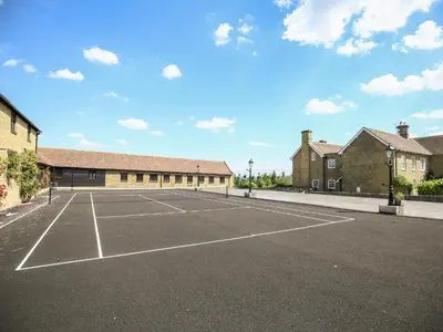 a tennis court in front of a building at Norton Cottage in Craven Arms