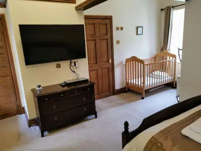 a bedroom with a flat screen tv and a crib at Lovely Large home 10 Minute Walk to Barmouth Beach in Barmouth