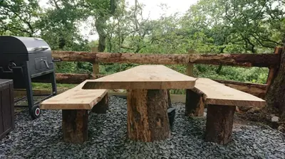 a picnic table and a grill next to a wooden fence at Owl Hut Cosy Ensuite Pod Snowdonia Coast Sleeps 2 in Dolgellau