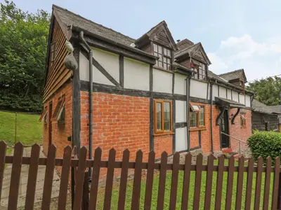 a brick house with a fence in front of it at Caerau Farm House in Llanidloes