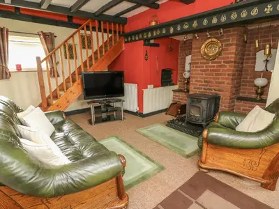 a living room with leather furniture and a fireplace at Caerau Farm House in Llanidloes