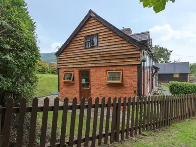 a brick house with a fence in front of it at Caerau Farm House in Llanidloes