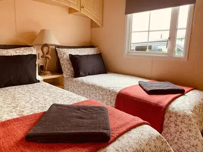 a bedroom with two beds and a window at 157 Amour Caravan in Tywyn