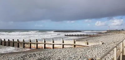 a beach with a wooden fence and the ocean at 157 Amour Caravan in Tywyn