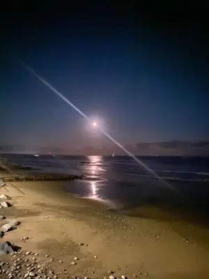 a view of a beach at night with the moon at 157 Amour Caravan in Tywyn