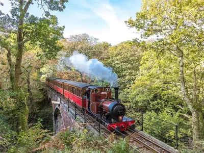a steam train on a bridge with smoke coming at 157 Amour Caravan in Tywyn