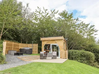 a wooden gazebo with a grill in a yard at Woodland Pod in Corwen