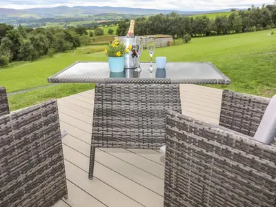 a patio with a table and two chairs and a view at Woodland Pod in Corwen
