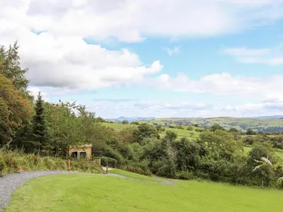 a path through a field with trees and a sky at Woodland Pod in Corwen