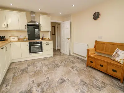 a kitchen with white cabinets and a bench in it at Lower Pentre in Llandrindod Wells