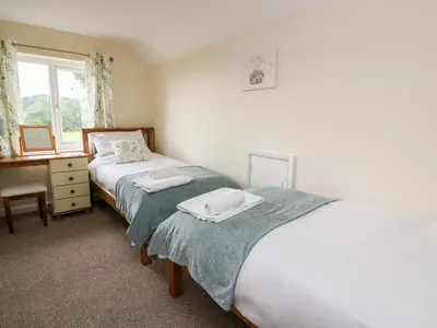 a bedroom with two beds and a desk and a window at Lower Pentre in Llandrindod Wells