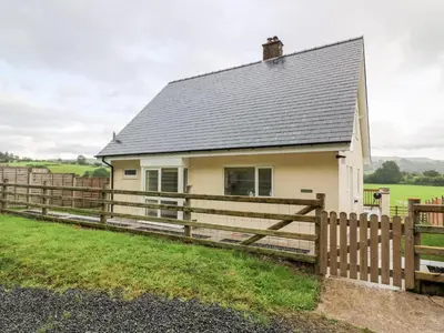 a small white house with a wooden fence at Lower Pentre in Llandrindod Wells
