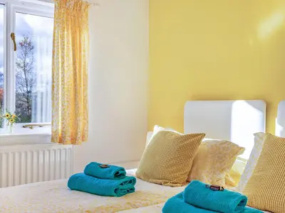 a bedroom with blue towels on a bed with a window at Cuckoo Hill Lodge in Saint Harmon