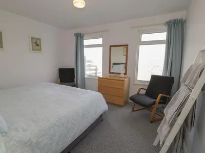 a bedroom with a bed and a desk and two chairs at Hafod-y-Gors in Fairbourne
