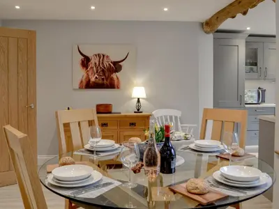 a dining room with a glass table with a cow on the wall at Cwm Dulas in Llanddewi-Brefi