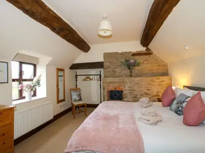 a bedroom with a large white bed with pink pillows at Wilstone Cottage in Church Stretton