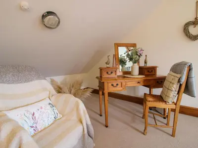 a bedroom with a desk with a mirror and a chair at Wilstone Cottage in Church Stretton