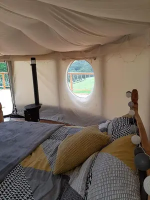 a bedroom with a bed in a tent with a window at Cae Mawr Yurt Off-Grid Glamping in Machynlleth