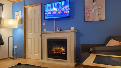 a living room with a fireplace with a tv on the wall at Foxs Lair Aberdovey in Aberdyfi