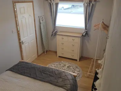a bedroom with a bed and a window and a dresser at Foxs Lair Aberdovey in Aberdyfi