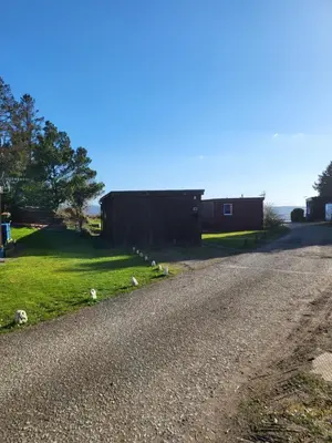 a gravel road next to a barn with sheep on it at Foxs Lair Aberdovey in Aberdyfi