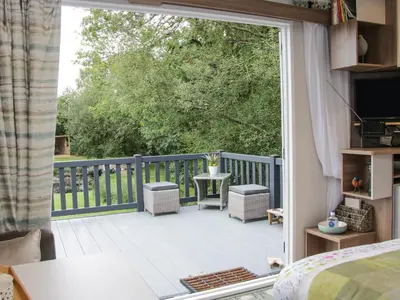 an open door to a deck with a table and chairs at Jacob's Meadow in Shrewsbury