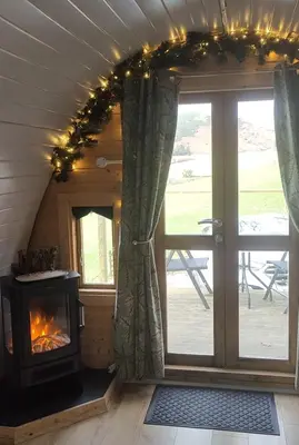 a fireplace in a tiny house with a window at Tan-y-Dderwen Pod in Machynlleth