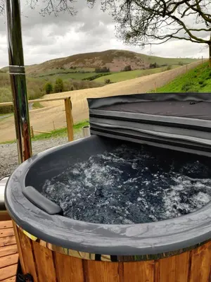 a hot tub filled with water in a field at Tan-y-Dderwen Pod in Machynlleth