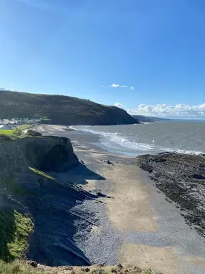 a beach with rocks and the ocean on a sunny day at Chalet 5 Clarach Bay in Aberystwyth