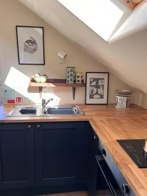 a kitchen with black cabinets and a sink at Snowdonia Hideaway in Tywyn