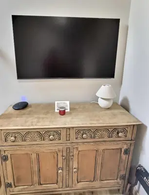 a television on top of a wooden dresser with a lamp at Snowdonia Hideaway in Tywyn