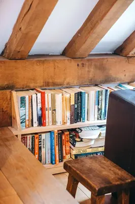 a book shelf filled with books next to a wooden bench at the garden room in Shrewsbury