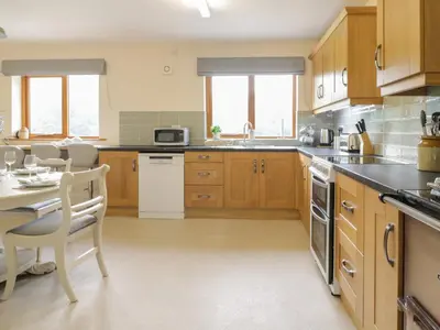 a kitchen with wooden cabinets and a table and chairs at Hendre in Oswestry