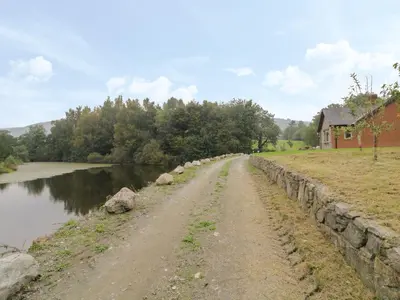 a dirt road next to a river next to a house at Hendre in Oswestry