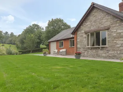 a stone house with a lawn in front of it at Hendre in Oswestry