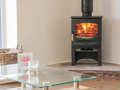 a wood stove in a living room with a glass table at Black Lion Barn Retreat in Shrewsbury