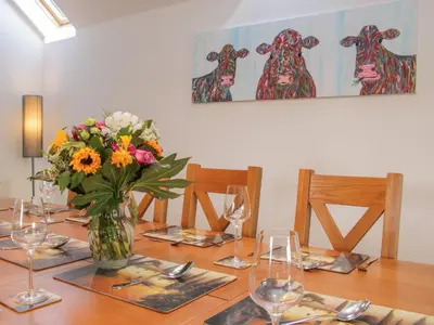 a wooden table with a vase of flowers and wine glasses at Black Lion Barn Retreat in Shrewsbury