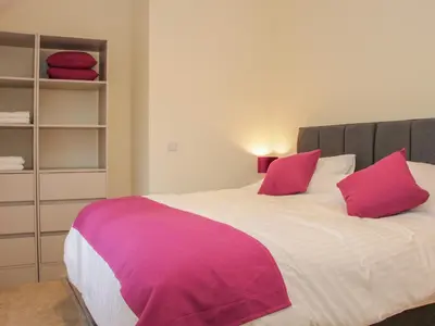 a bedroom with a large bed with pink pillows at Black Lion Barn Retreat in Shrewsbury