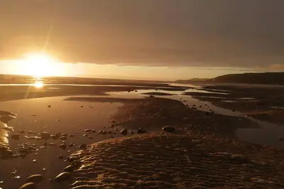 a sunset over a body of water with the sun setting at Bwthyn Gweilch in Machynlleth