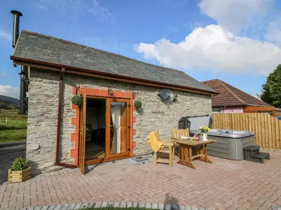 a small stone cottage with a table and a grill at Tegfan Barn in Rhayader