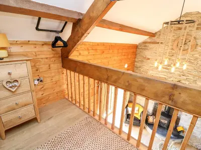 an attic room with wooden walls and a wooden staircase at Tegfan Barn in Rhayader