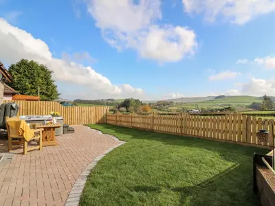 a backyard with a wooden fence and a table at Tegfan Barn in Rhayader