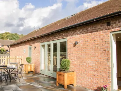 a brick house with a patio with a table and chairs at Conkers' Cottage in Church Stretton