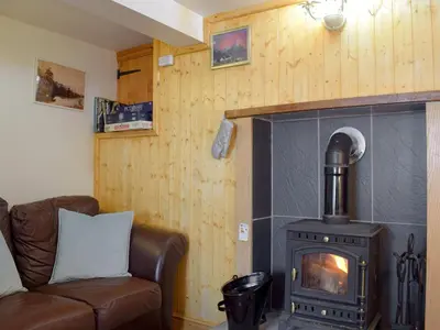 a living room with a wood stove and a couch at Paramount Cottage in Farden