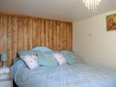 a bedroom with a blue bed with a wooden wall at Paramount Cottage in Farden