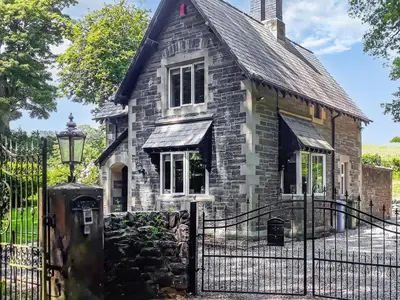 an old stone house with a black fence at Llantysilio Lodge in Llangollen