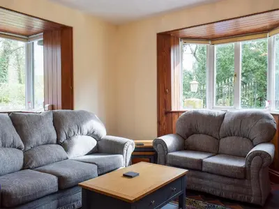 a living room with two couches and a table at Llantysilio Lodge in Llangollen